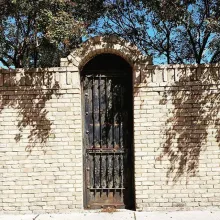 Black iron gate in an arched brick wall